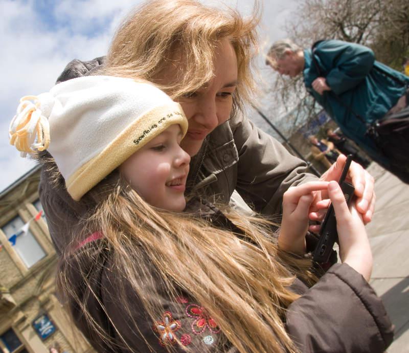 A mother and daughter looking at phone screen showing an augmented reality monster they have found in Bacup in 2010.